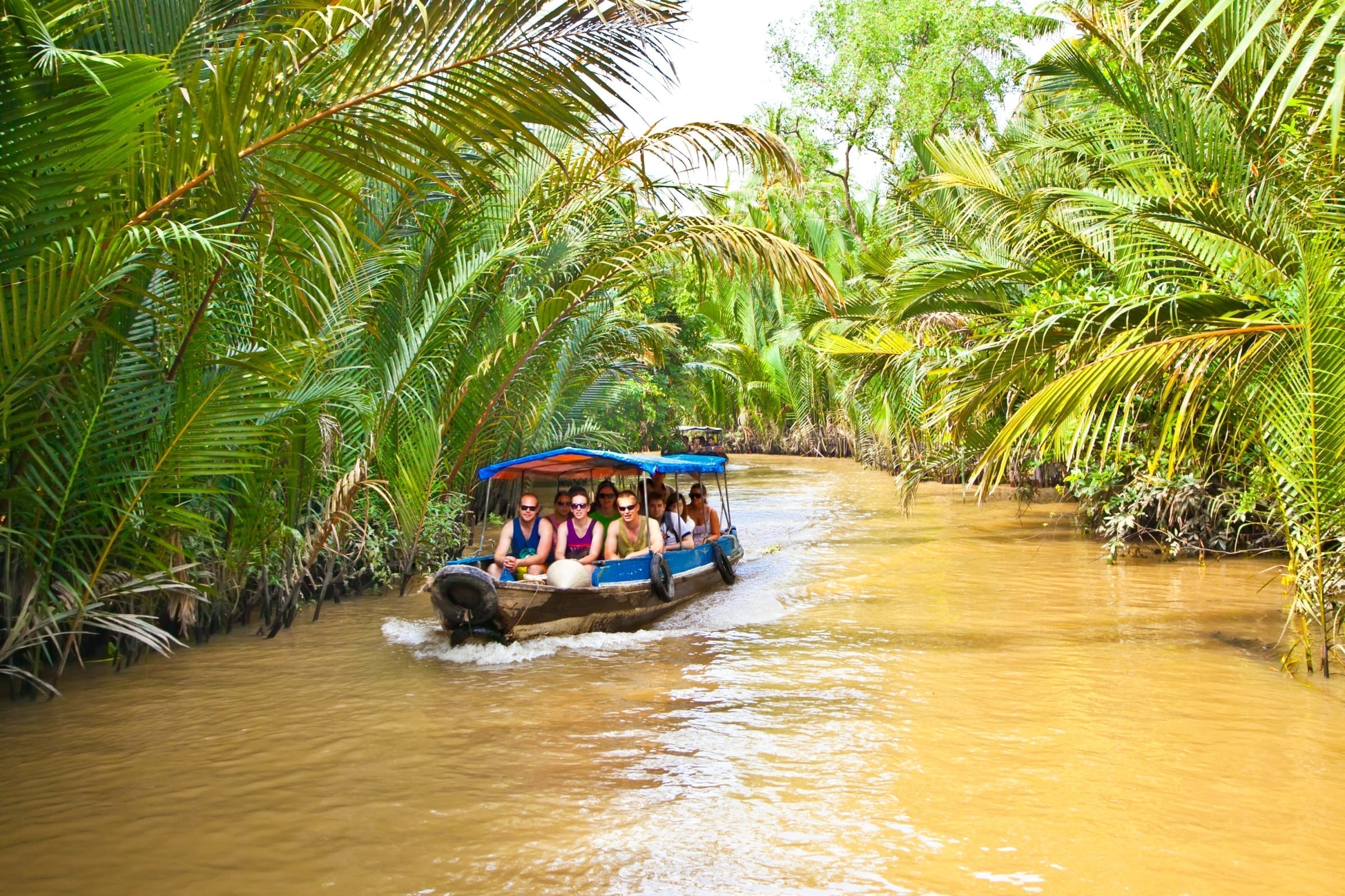 Tourists on boat cruising along Mekong River in Ben Tre, Vietnam, included in tours offered by Asia Vacation Group