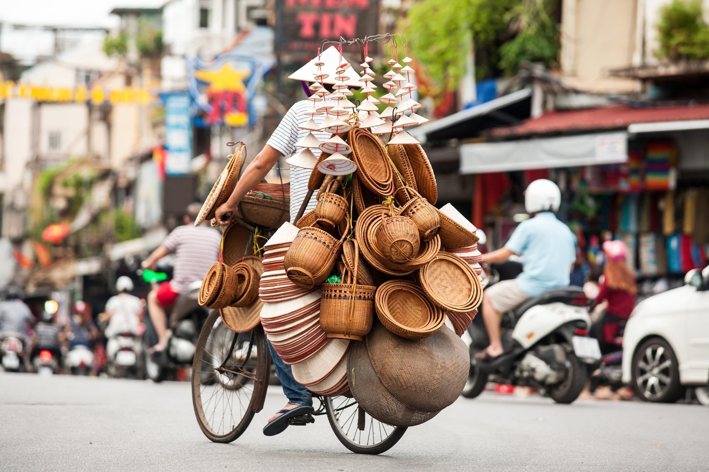 Hanoi Street vendor selling straw hat, included in tours offered by Asia Vacation Group