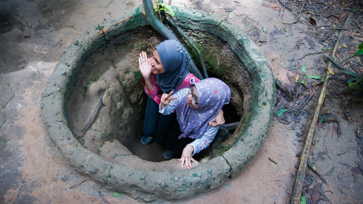 Two girls sneaking in Cu Chi Tunnels, Saigon, Vietnam, included in tours offered by Asia Vacation Group